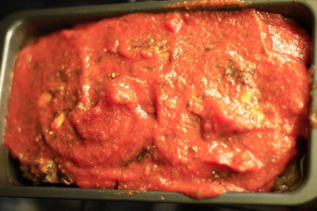 Meatloaf baking with a topping of pasta sauce