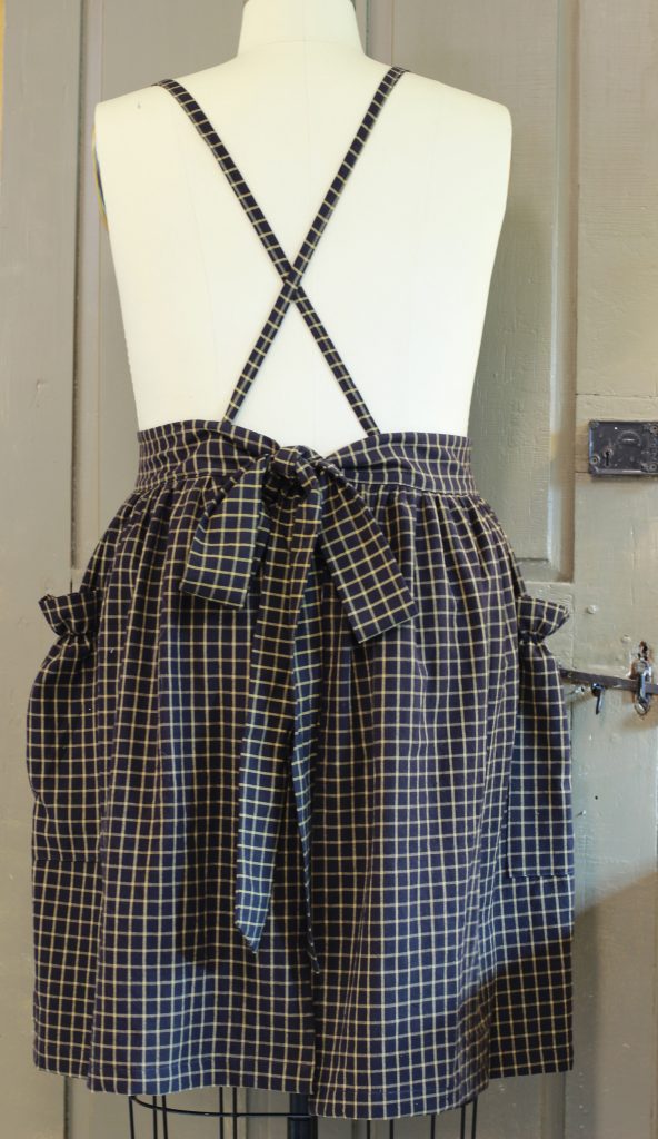 Gathered Bib Apron with its straps crossed and waist ties tied in back.